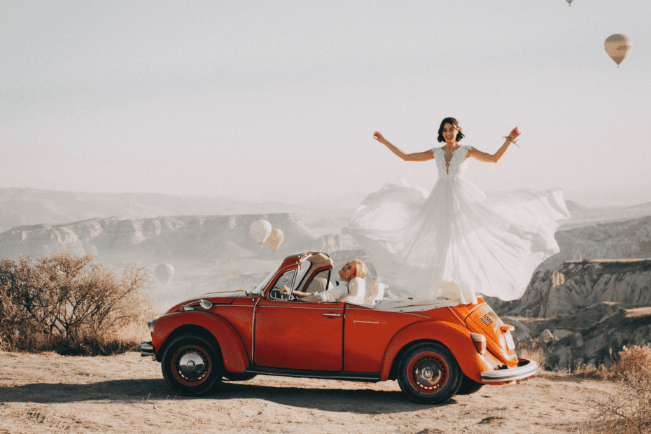 Femme marié avec une robe blanche sur une voiture rouge qui fait un voyage en amoureux